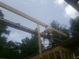 Carpenter setting a ridge beam over a new addition frame — Ice Dam Removal by Roofing Brothers in Jenners