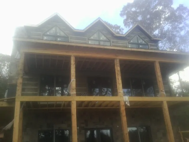 Dormers and porch framing on a large log home under construction — Roof Coating work by our crew in Jenners
