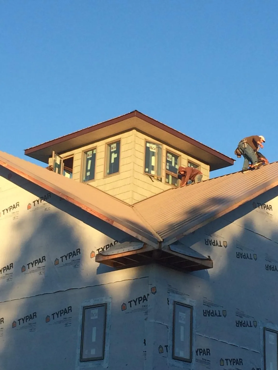 Roofers working around a rooftop cupola on a new metal roof at sunset — Roof Waterproofing in Jenners by Roofing Brothers